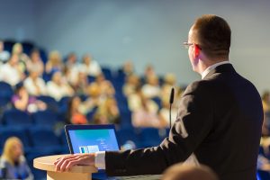 Speaker giving a talk on corporate Business Conference. Audience at the conference hall. Business and Entrepreneurship event.